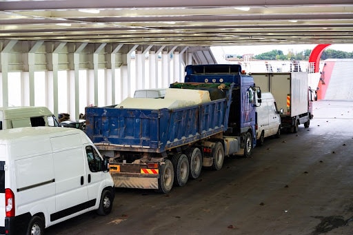 Trucks and white vans lined up on the vehicle deck of a ferry boat in Greece.